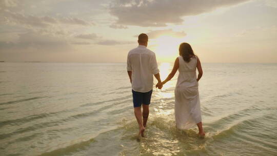 年轻夫妇在海边漫步看日落