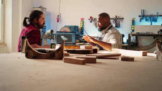 快乐的橱柜制造商和同事在细木工中交谈
