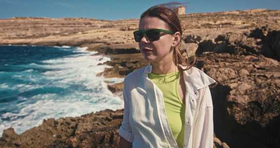 地中海生活方式的女人在海边沿着岩石散步的