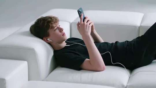 男子躺沙发上玩手机
