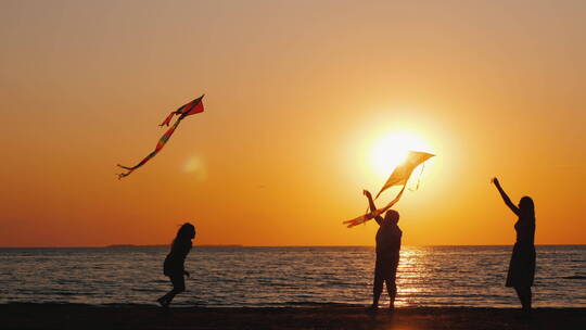 傍晚在海边放风筝的家人