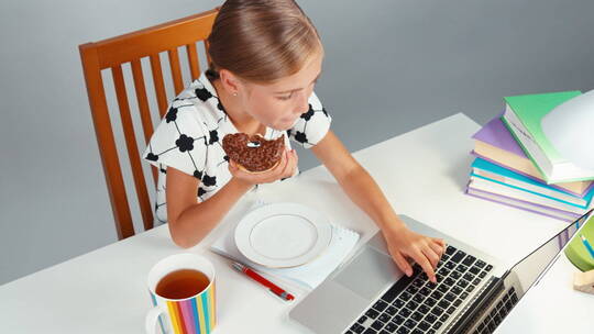 吃着甜甜圈使用电脑的女孩