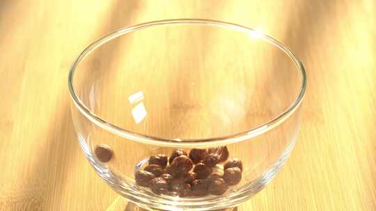 巧克力麦片落在碗里。日出时用玻璃倒的健康