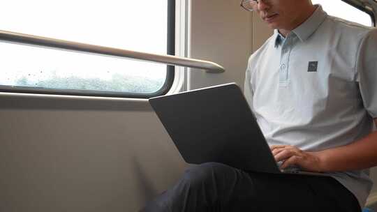 中年男子在火车上使用笔记本电脑工作