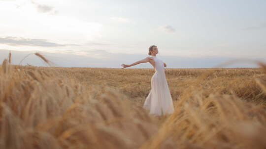 身穿白色连衣裙的迷人女性在田野中跳舞