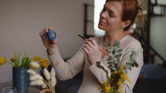 一个孕妇手里拿着一个复活节彩蛋，用画笔修