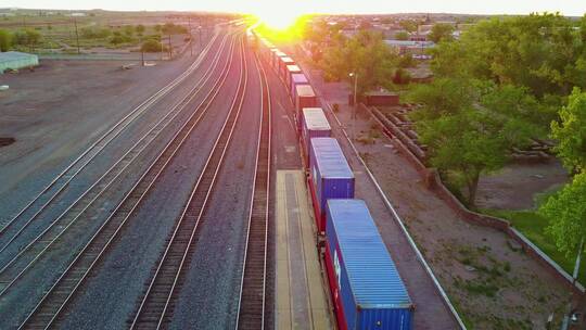 高空飞过一列满载出口集装箱的货运列车，驶向日落