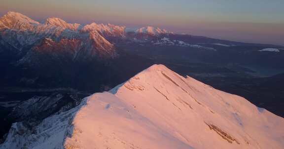 日落时分，无人机俯瞰积雪覆盖的阿尔卑斯山