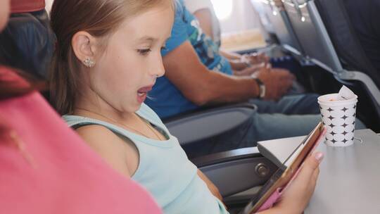 飞机上小女孩在看平板电脑视频素材模板下载