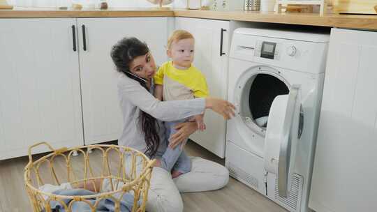 漂亮的妈妈打电话上班，把衣服放在洗衣机里，儿子在旁边玩耍。