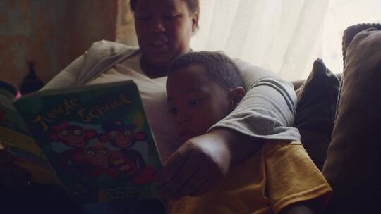  妈妈坐在沙发上陪儿子看书