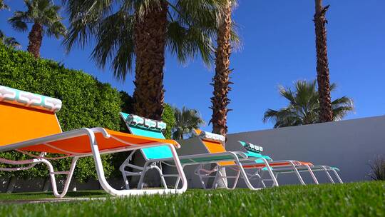 棕榈泉一户人家的游泳池周围坐着五颜六色的草坪椅