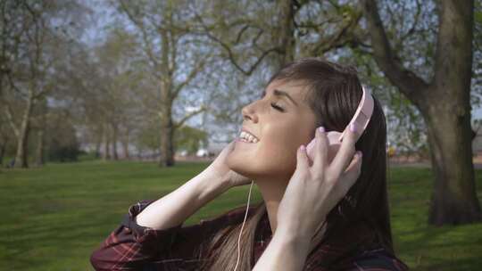 白人女性在公园里通过耳机慢动作听音乐