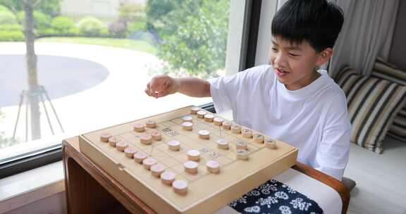 可爱的男孩在窗边下中国象棋