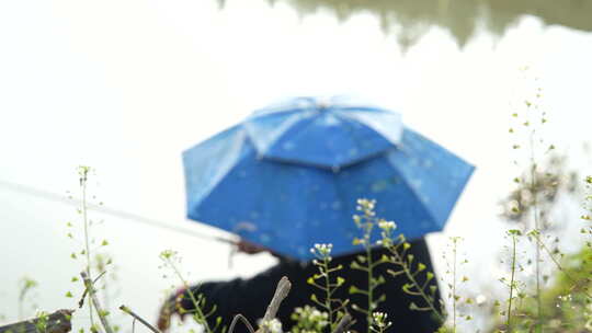 头戴一顶蓝色伞帽在河边钓鱼