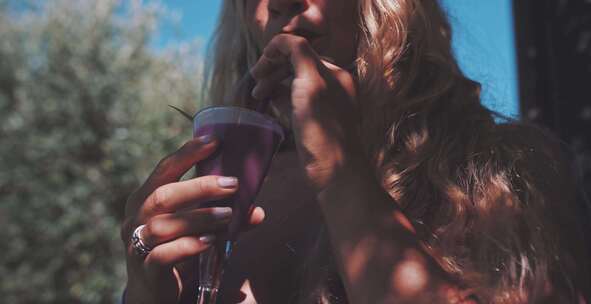 女人用吸管啜饮紫色饮料