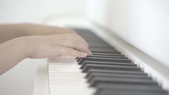 一个7岁的小女孩正在用两只手弹一架白色钢