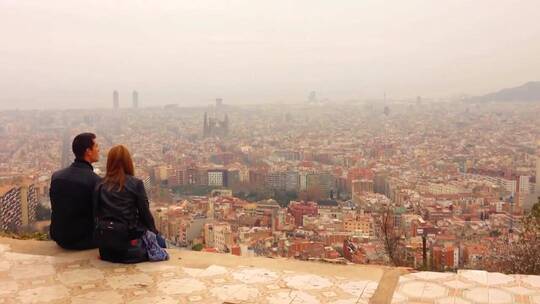 情侣坐在高地看城市景观