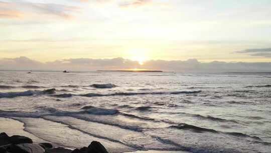 清晨海岸海浪拍打沙滩海浪翻滚渔船出海日出