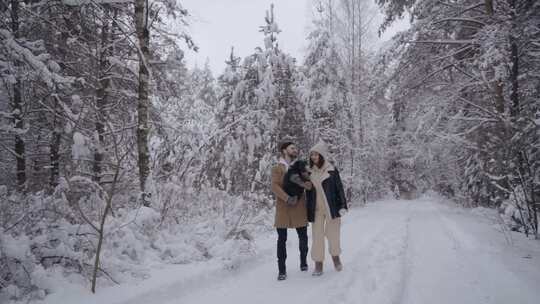 一对夫妇带着他们的狗在雪地里散步