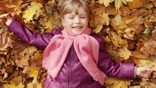 躺在枫叶上的小女孩微笑这挥手