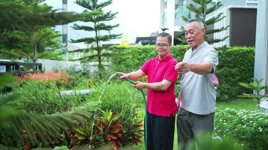 在他们的休息日祖父和孙子帮助浇水的树木在