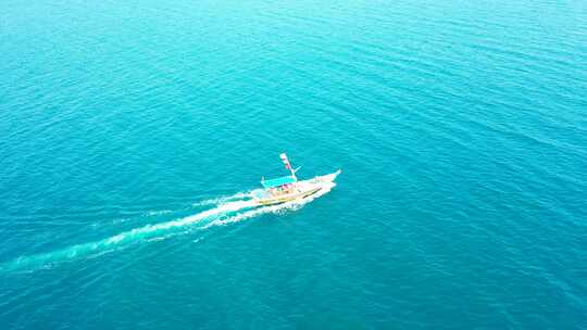 游览船在蔚蓝的海面上缓慢航行，充满活力的水面反射着明亮的蓝天
