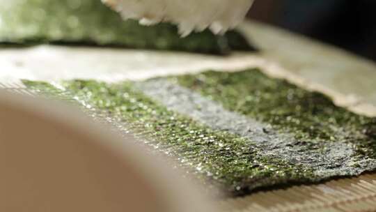 制作寿司往海苔上放米饭