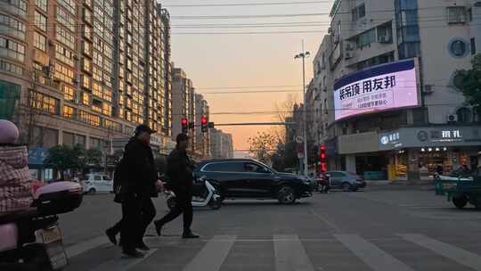 城市街道的红绿灯路口：车流与行人傍晚景象