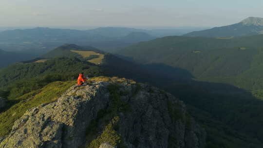 坐在落基山顶上俯瞰深谷的男性徒步旅行者视频素材模板下载