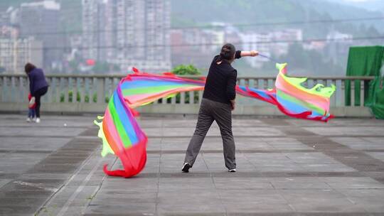 中年女性舞动彩色飘带的户外场景