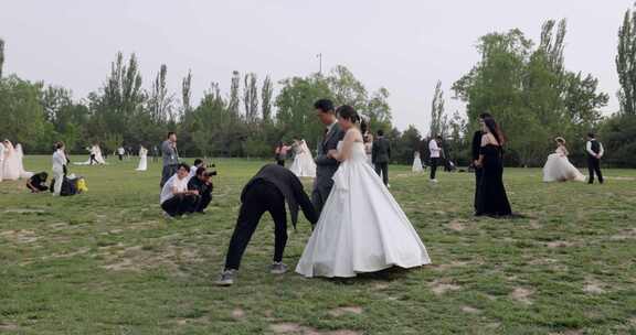 草坪上拍摄婚纱照的新婚情侣们