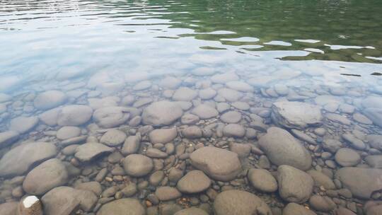 鹅卵石清澈水面随微风缓缓流淌背景