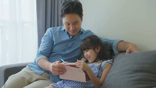 亚洲小女孩在家与慈爱的父母一起学习在线课程。视频素材模板下载