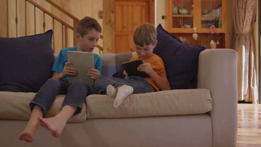 两个男孩在家里玩平板电脑