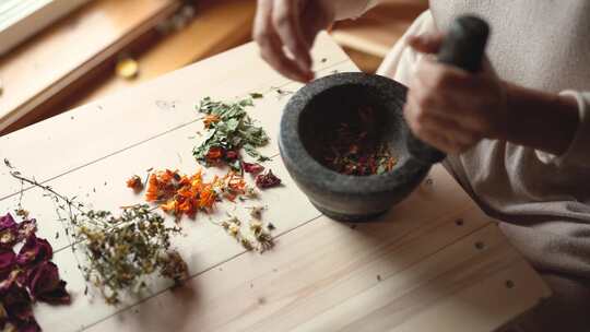 一个把干草药放在砂浆和杵里的人