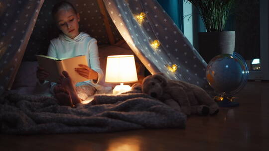 可爱的女孩在帐篷里看书