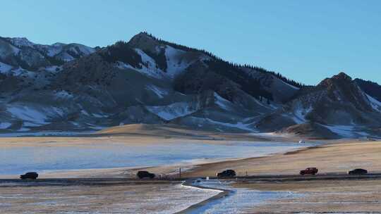 航拍冬季新疆赛里木湖雪山环湖公路夕阳车辆