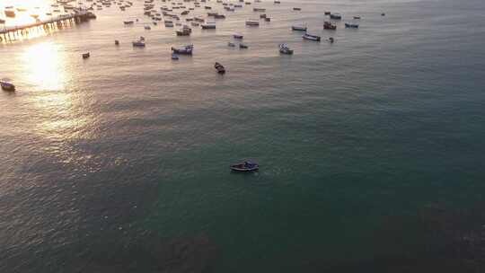 一艘船在海洋中划船的无人机视频。许多船只停泊在它上面和远处的码头上。拍摄d