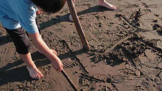 孩子们用棍子在沙滩上写字