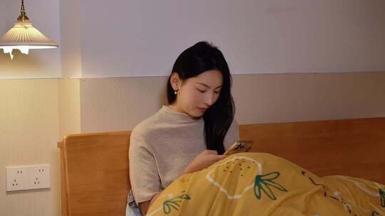 夜晚女生躺床上看手机