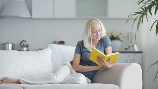 年轻女子坐在沙发上看书 