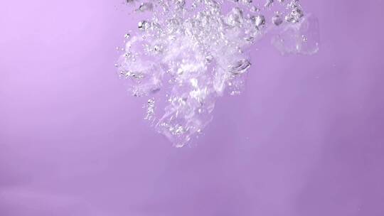 冰块落入紫色背景的水中视频素材模板下载