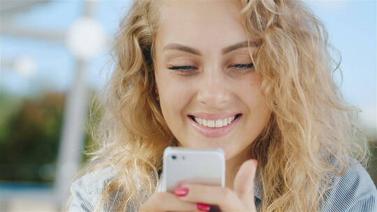 一个迷人的年轻女人微笑着看着手机屏幕