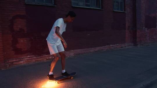 一个年轻人在玩滑板在滑板下放着点燃的烟花