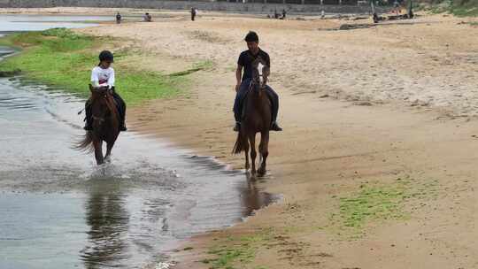航拍威海市环翠区金海路沙滩上的骑马人
