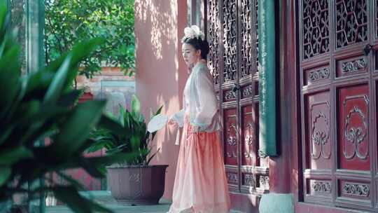 古装女子持扇立于古门前