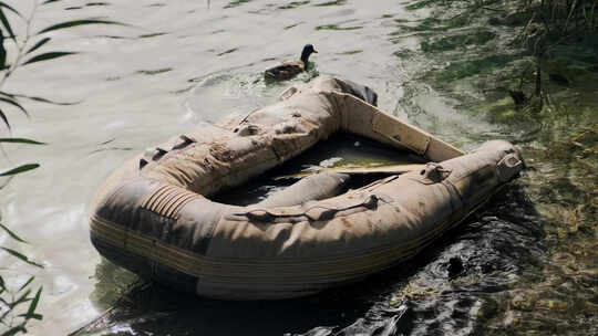 河岸附近废弃的橡皮艇鸭子坐在上面跳进水里