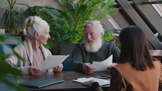 老年白人夫妇在咖啡馆与女代理人签署保险单
