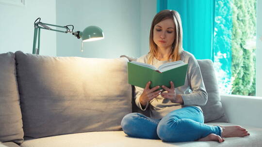 年轻的女人在沙发看书
